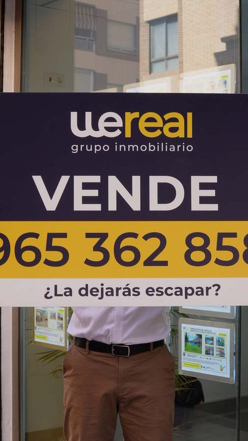 Wereal Grupo Inmobiliario "For sale" sign in the window of a home in Alicante