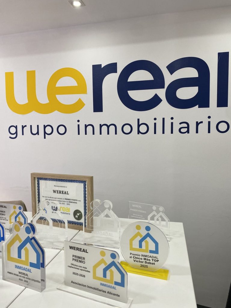 Wereal Grupo Inmobiliario logo and INMOADAL awards in the Alicante office